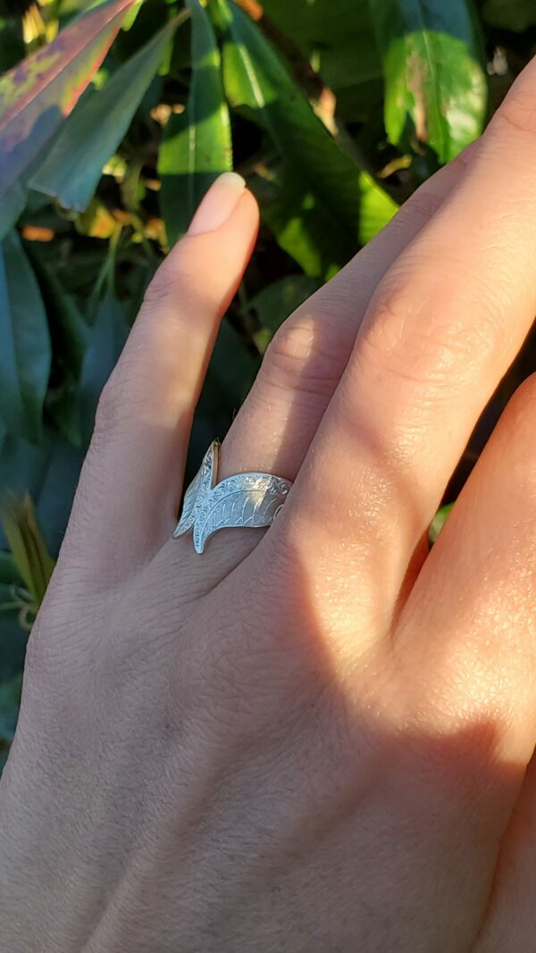 Bague de fiançailles sur main devant verdure