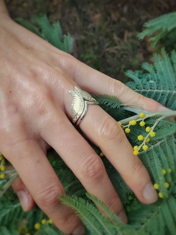 Main de femme sur mimosa portant bague de fiançailles et alliance