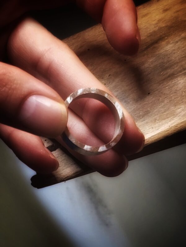 Main tenant une bague en cours de fabrication à l'établi