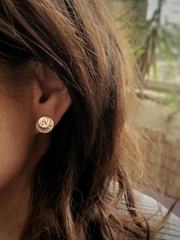 Femme de profil portant une petite boucle d'oreille ronde gravée.