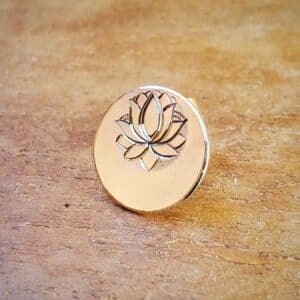 Puce d'oreille gravée d'un lotus. Sur support en bois.