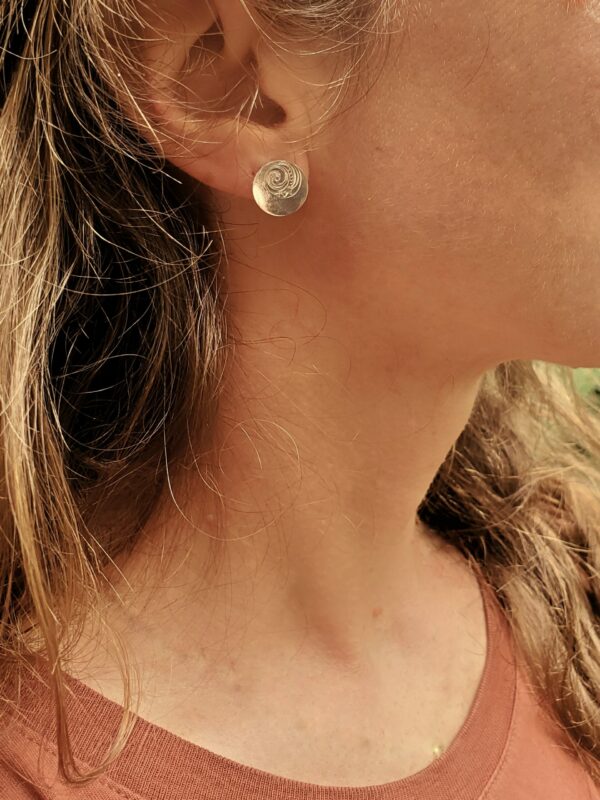 Profil de femme portant une petite boucle d'oreille ronde gravée.