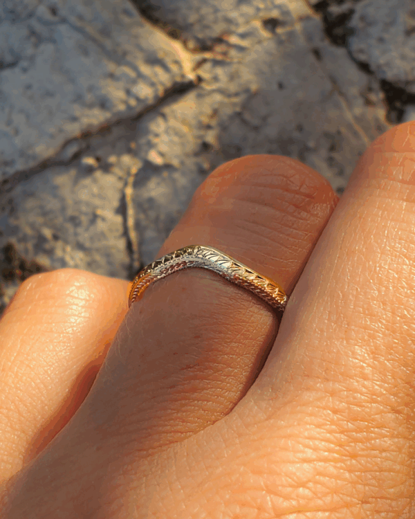 Bague Leialta, incurvée et ornée de gravures végétales, portée sur doigt.