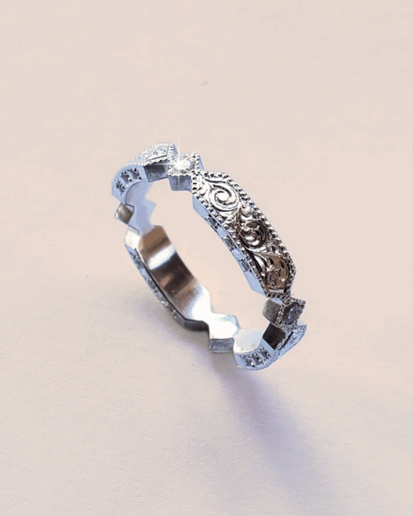 Alliance en or gris romantique ornée de volutes, de gravures florales et de diamants.