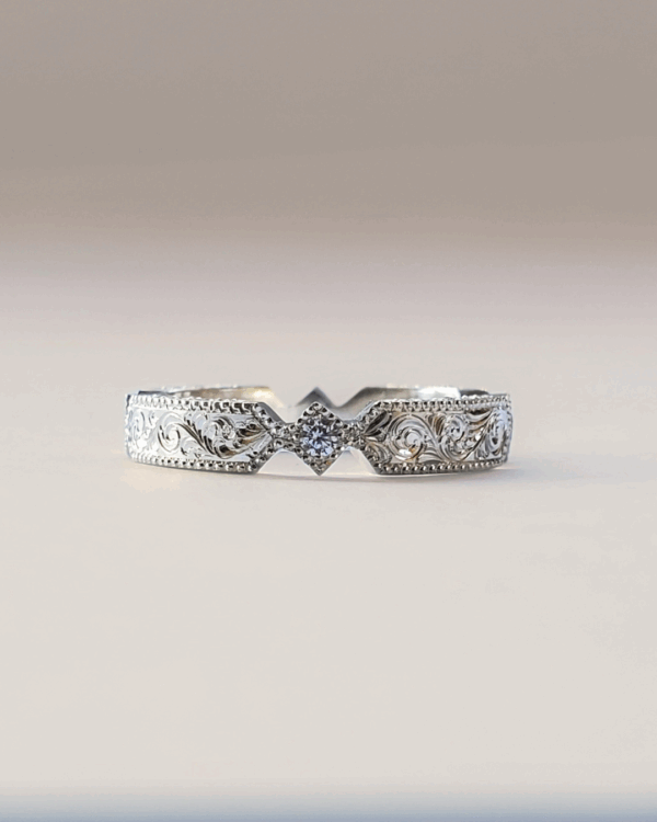 Alliance en or gris romantique ornée de volutes, de gravures florales et de diamants.