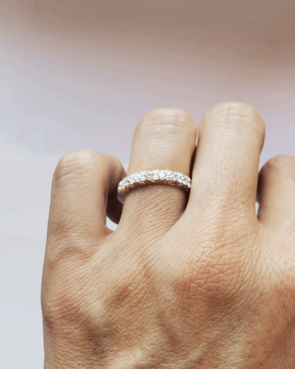 Bague de fiançailles ou alliance pavée de diamants brillants, portée au doigt.