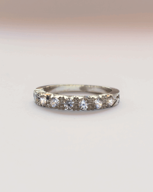 Bague de fiançailles ou alliance en or gris pavée de diamants. Posée sur fond clair.
